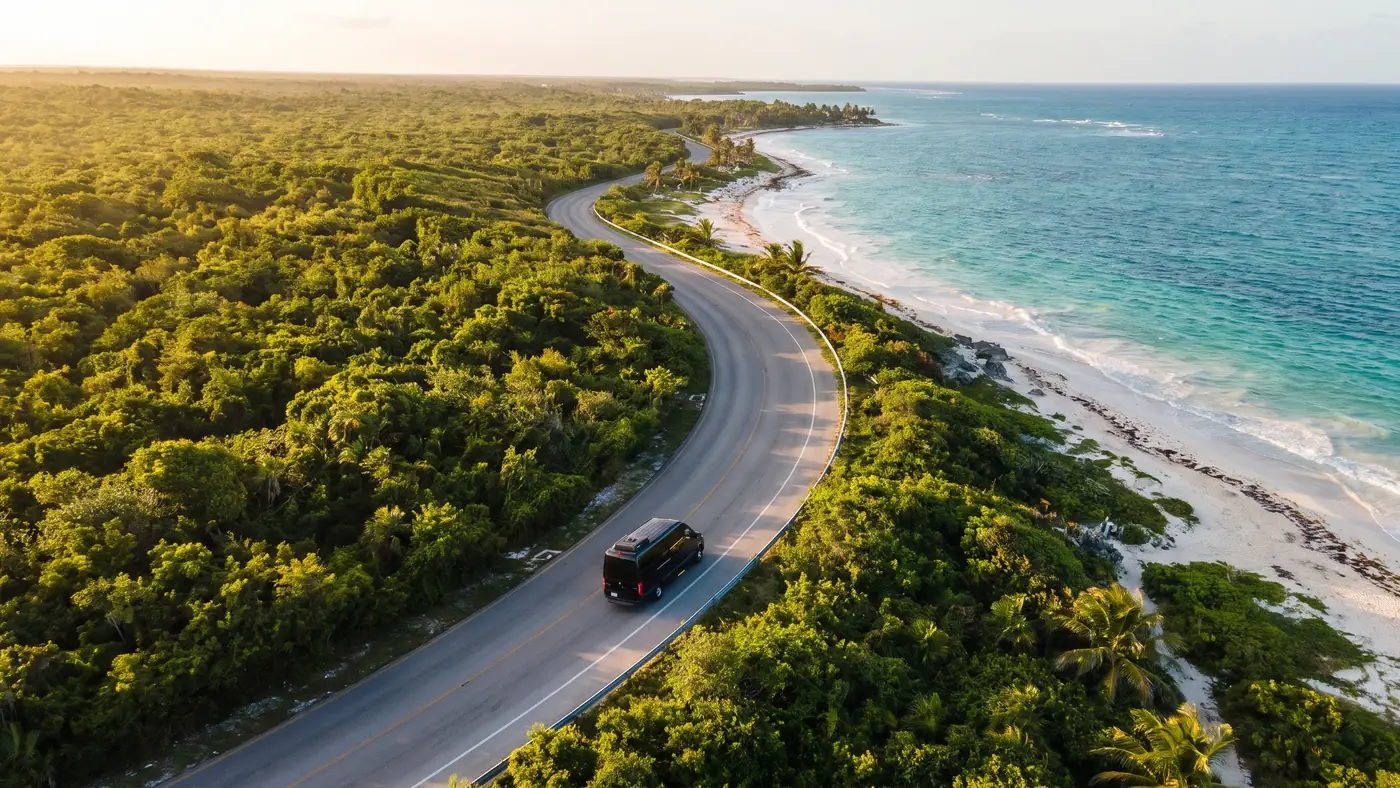 Van negra en una carretera costera entre selva y mar rumbo a Tulum